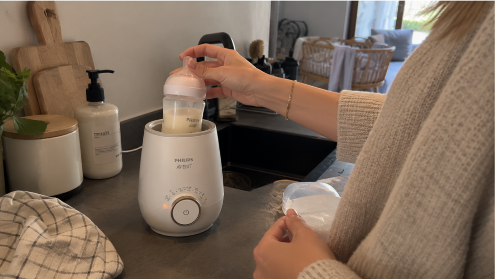 Ouder verwarmt een babyfles met een flessenwarmer tijdens een voedmoment thuis
